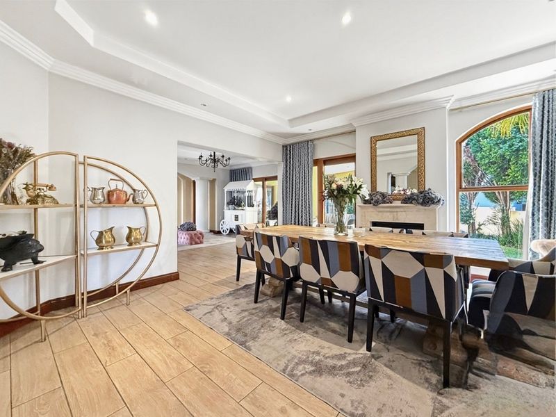 Spacious dining room featuring tiled flooring, a fireplace, and an arched window, with an open-plan flow into the adjacent living area.
