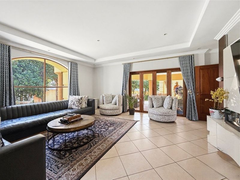Spacious living room featuring tiled flooring, a recessed ceiling, and large timber-framed glass doors providing access to the outdoor area.
