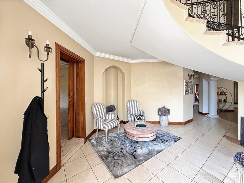 Spacious entrance foyer featuring tiled flooring, an elegant wrought iron staircase, and a decorative arched wall niche.