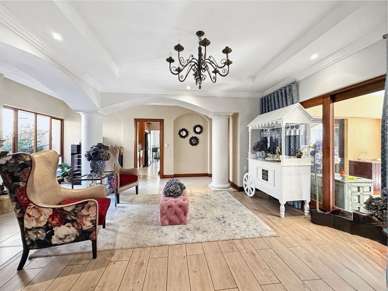 Spacious living area featuring elegant archways, decorative columns, recessed ceiling details, and timber-look tiled flooring with access to outdoor areas.
