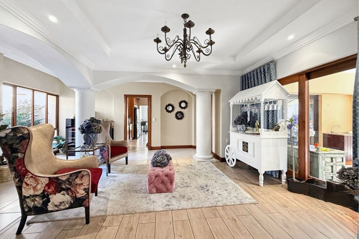 Spacious living area featuring elegant archways, decorative columns, recessed ceiling details, and timber-look tiled flooring with access to outdoor areas.
