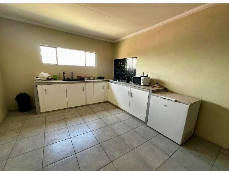 A functional kitchen featuring tiled flooring, built-in cabinetry, and a tiled backsplash, offering a practical layout for daily meal preparation.