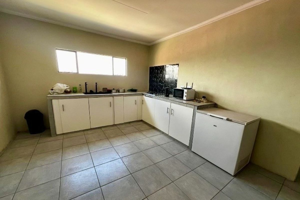 A functional kitchen featuring tiled flooring, built-in cabinetry, and a tiled backsplash, offering a practical layout for daily meal preparation.