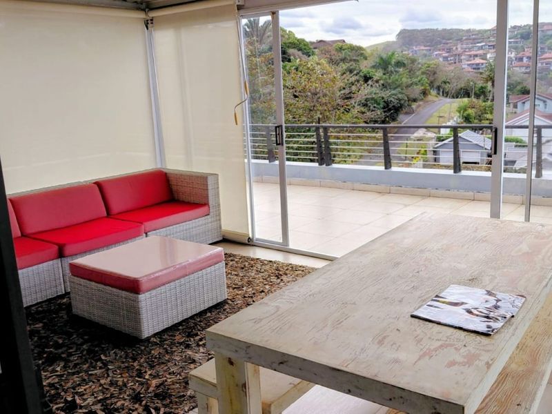 Spacious covered balcony featuring tiled flooring, retractable blinds, and sliding glass doors, offering an elevated view of the surrounding neighborhood.