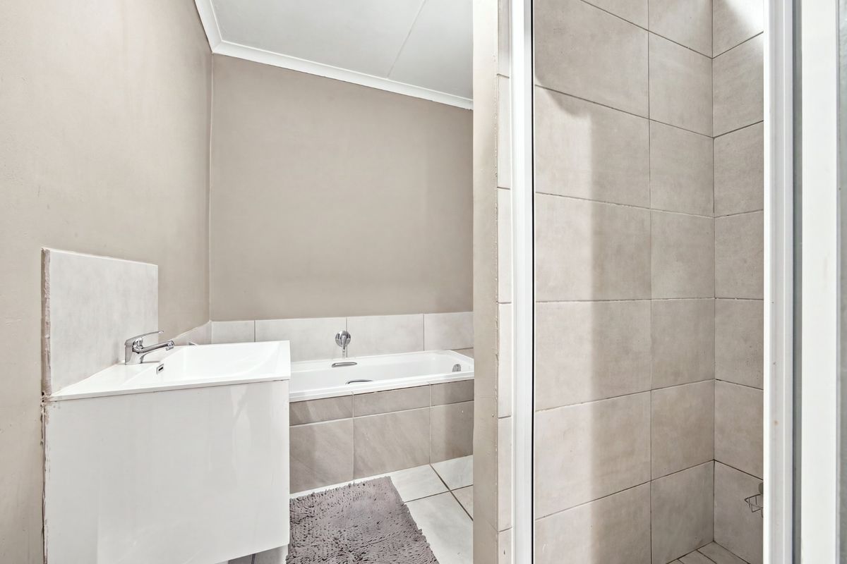 A clean, modern bathroom featuring a built-in bathtub, vanity basin, and a separate tiled shower enclosure with neutral finishes.