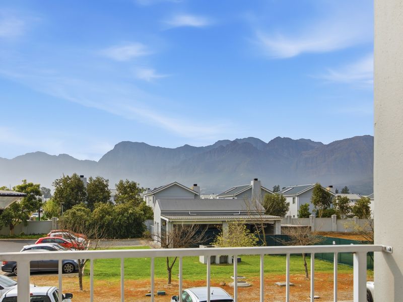 A scenic view from the balcony overlooking the surrounding residential estate with prominent mountain vistas in the background.