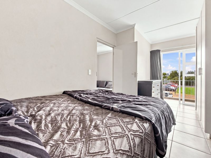 A bedroom featuring tiled flooring, built-in cupboards, and a sliding glass door providing access to a balcony.