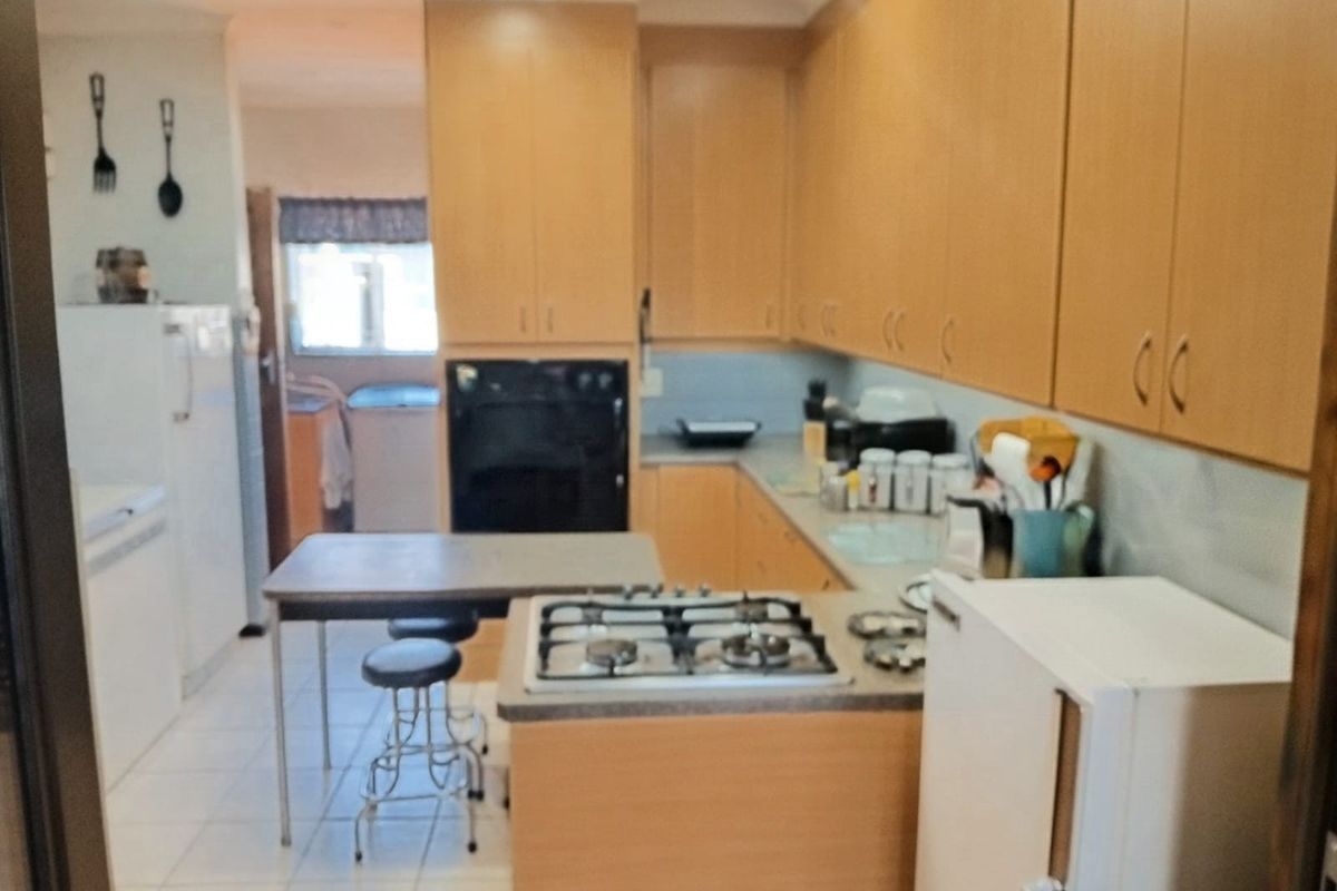 A functional kitchen featuring light wood-tone cabinetry, a gas cooktop, built-in oven, and tiled flooring, offering a practical layout for daily meal preparation.