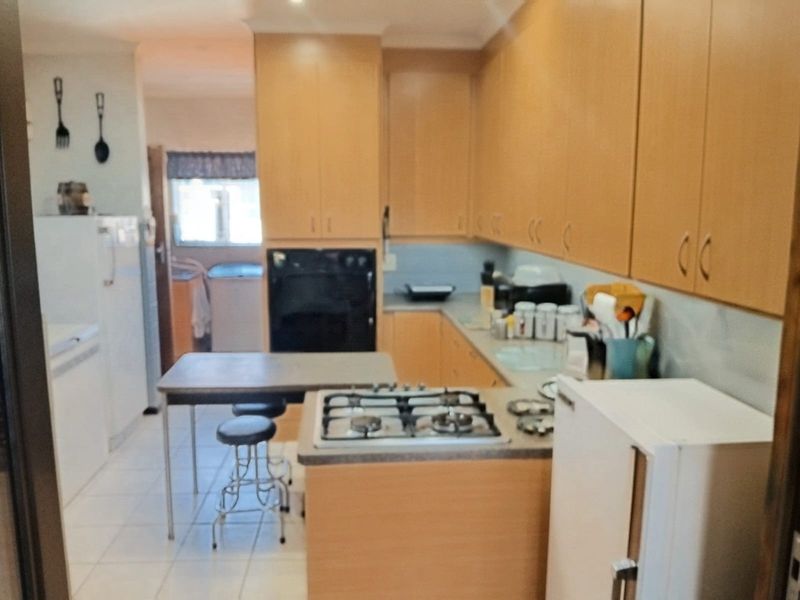 A functional kitchen featuring light wood-tone cabinetry, a gas cooktop, built-in oven, and tiled flooring, offering a practical layout for daily meal preparation.