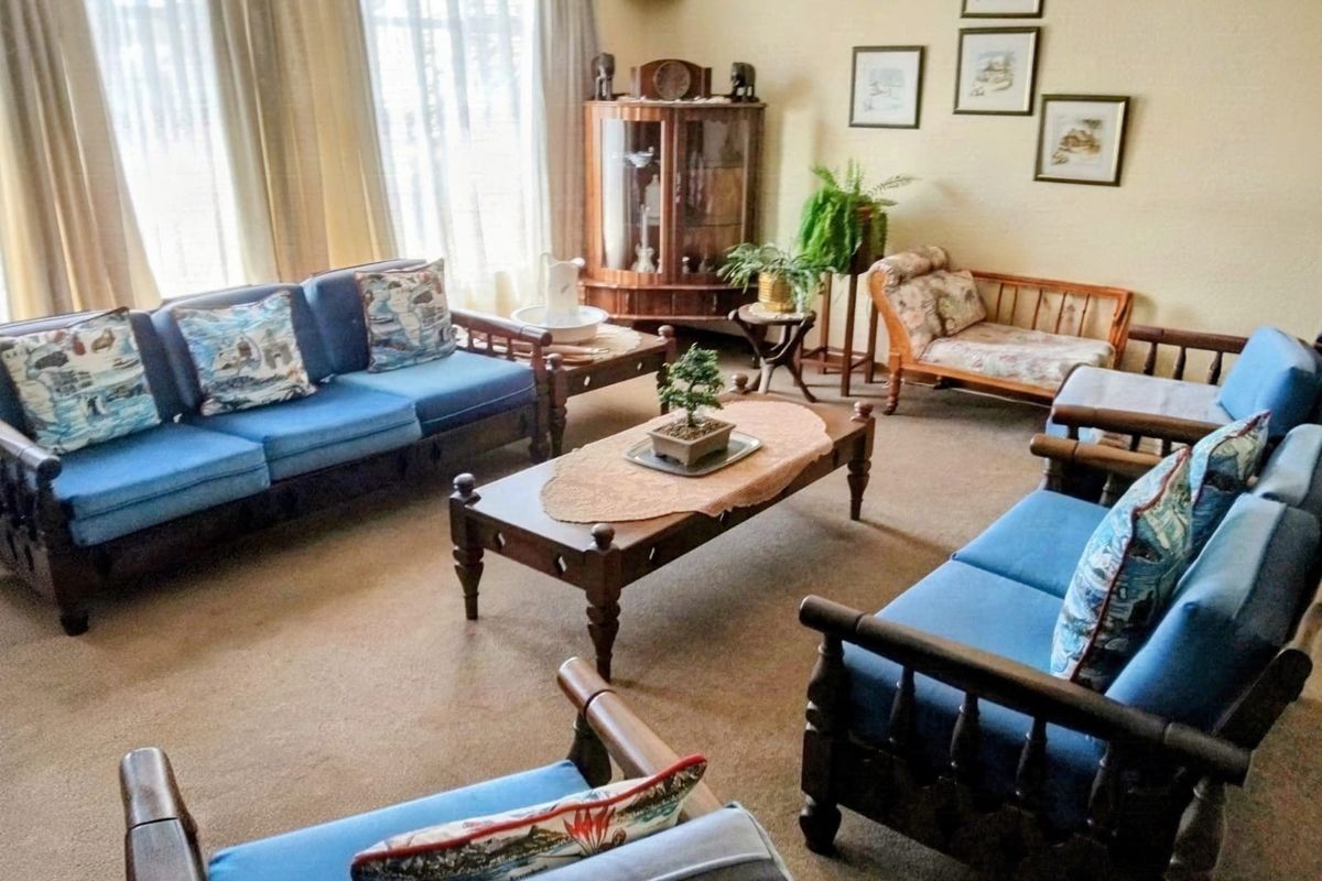 A spacious living room featuring carpeted flooring and large windows that provide ample natural light.