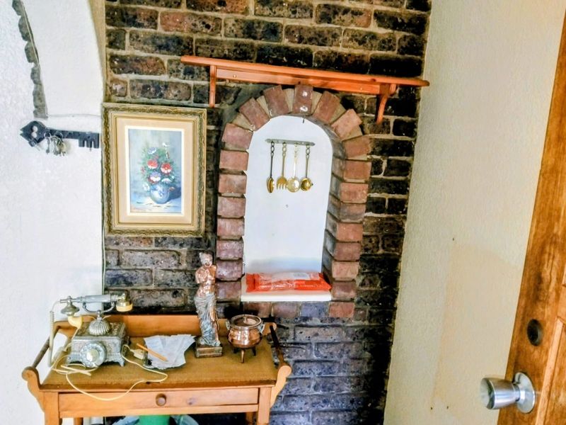 A living area feature wall showcasing an exposed brick finish with a decorative arched brick alcove and a mounted wooden shelf.