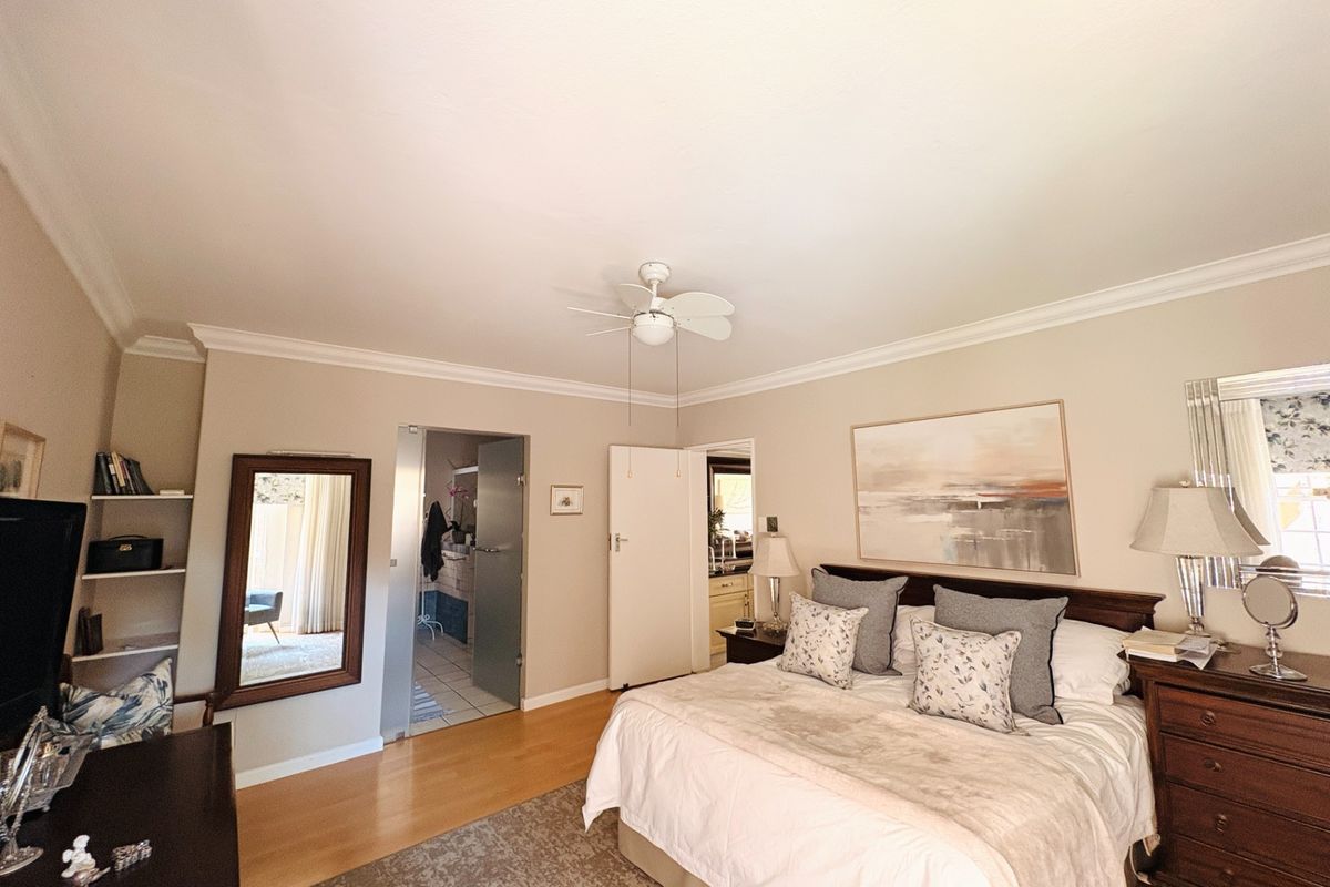 Spacious bedroom featuring laminate flooring, a ceiling fan, and integrated shelving, with direct access to an en-suite bathroom.