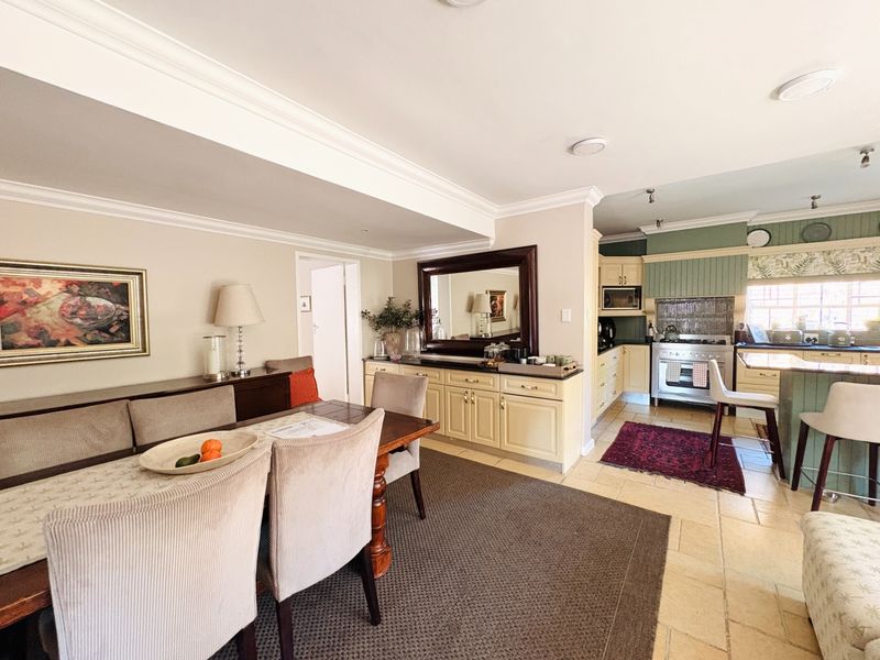 Spacious open-plan dining and kitchen area featuring classic cabinetry, stone tile flooring, and a built-in gas stove with an integrated extractor fan.