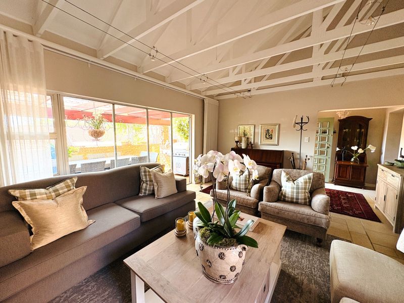 Spacious living room featuring a high vaulted ceiling with exposed timber rafters, stone flooring, and large sliding glass doors leading to an outdoor patio.