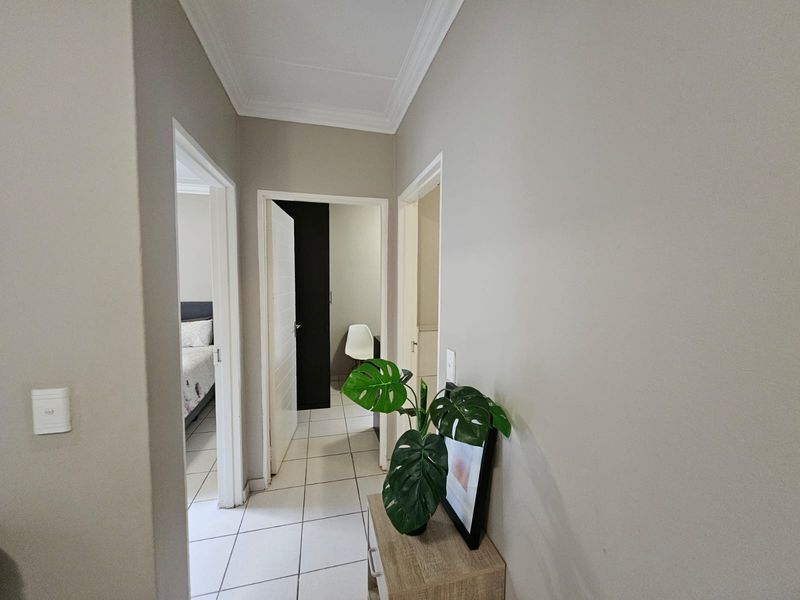 A clean and well-maintained hallway featuring neutral wall tones, tiled flooring, and classic cornicing, providing access to multiple rooms within the townhouse.