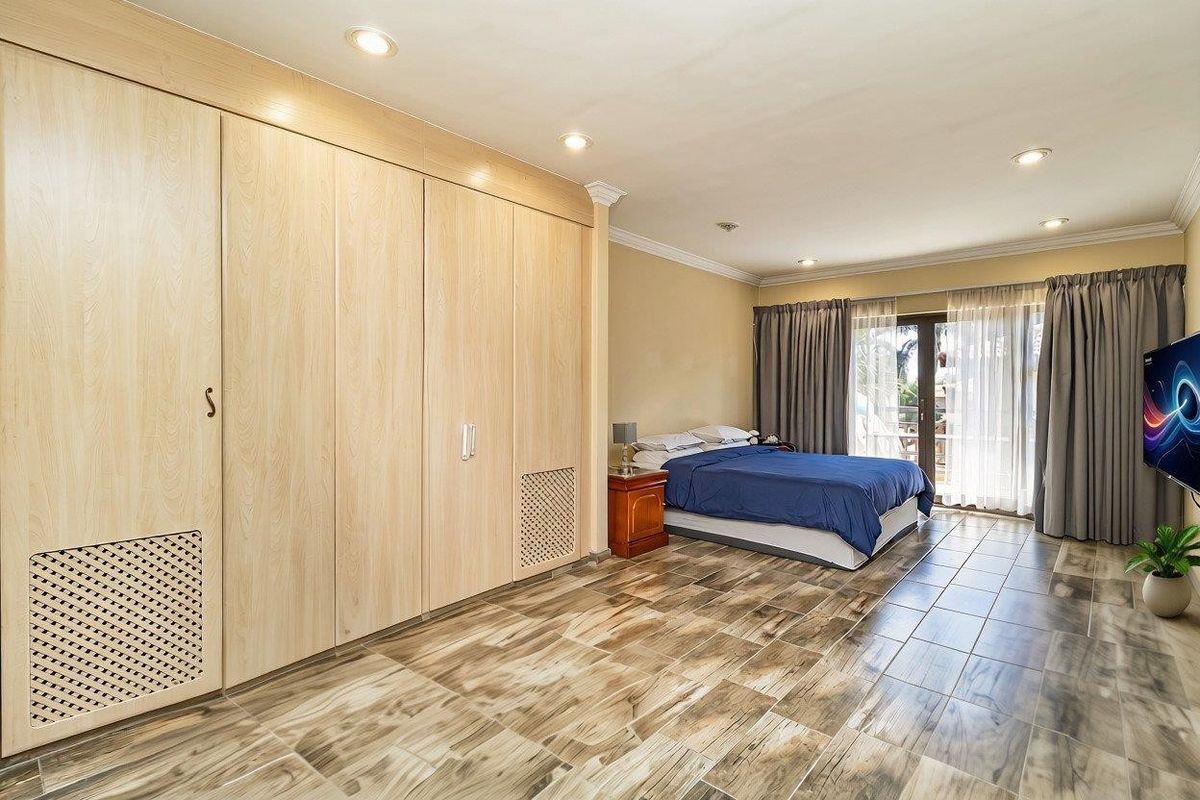 Spacious bedroom featuring extensive built-in wooden cabinetry, tiled flooring, recessed lighting, and direct access to an outdoor area through sliding glass doors.