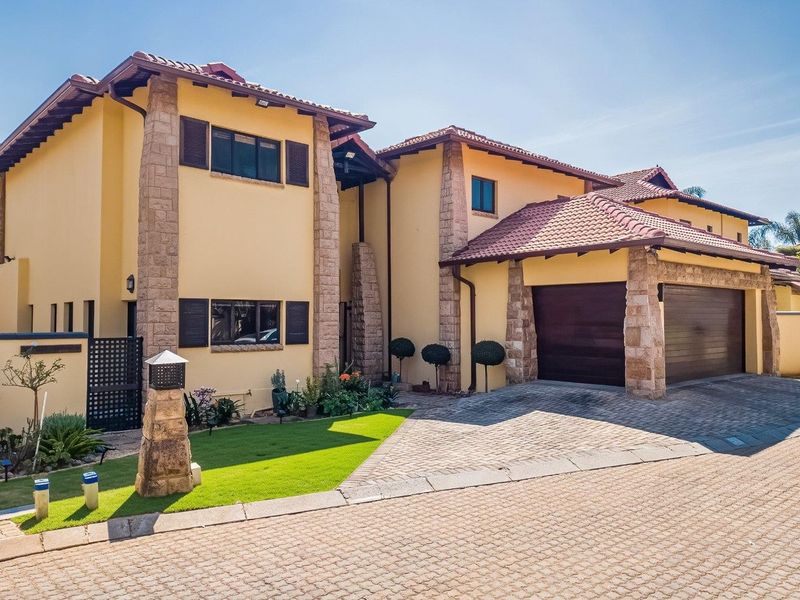 A well-maintained double-story residential property featuring stone-clad pillars, a tiled roof, and a paved driveway leading to a double garage.