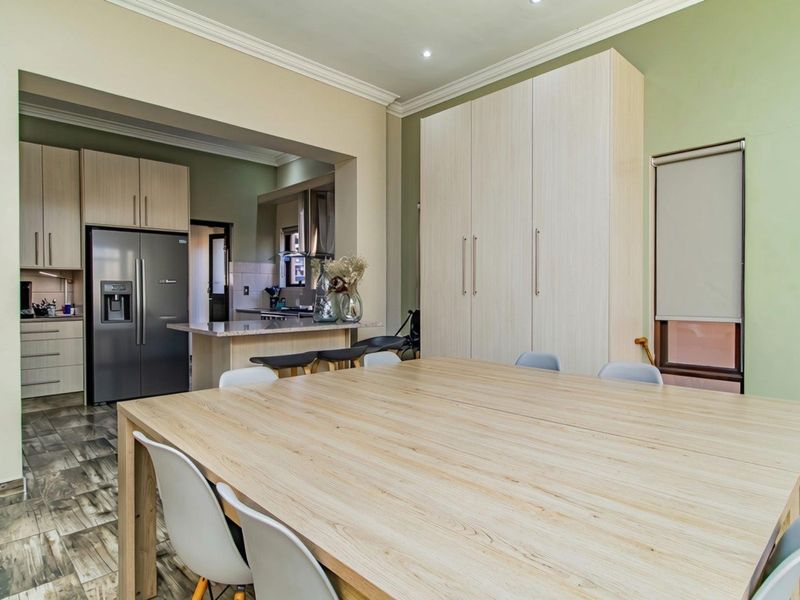 Open plan kitchen and dining area featuring modern built-in cabinetry, stone countertops, tiled flooring, and elegant crown molding.