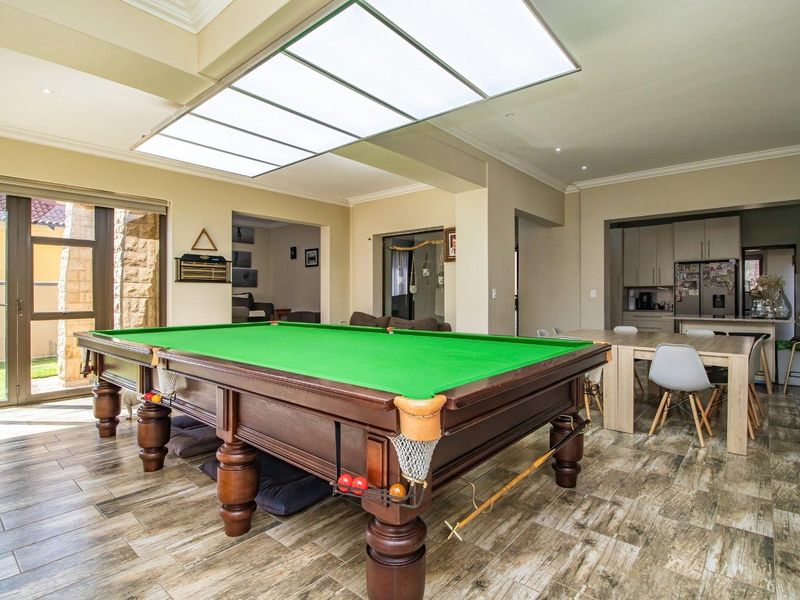 Spacious open-plan living area featuring a large skylight, tiled flooring, and seamless flow to the kitchen and outdoor patio area.