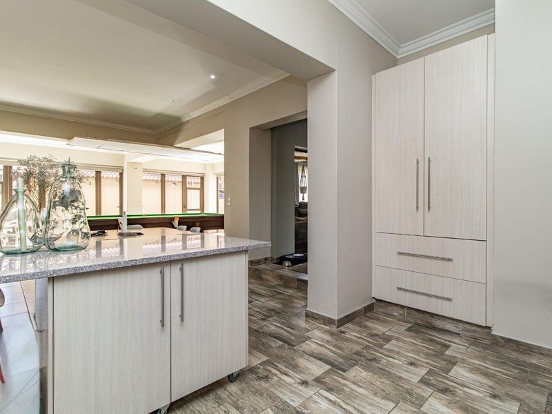 Open plan living area featuring modern light wood cabinetry, stone countertops, and durable wood-look tiled flooring with clean architectural lines.