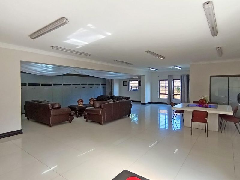 Spacious open-plan living and dining area featuring large format floor tiles, neutral walls, and extensive built-in cabinetry.