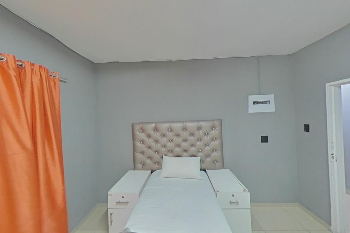 A bedroom featuring tiled flooring and an exposed electrical distribution board on the wall.