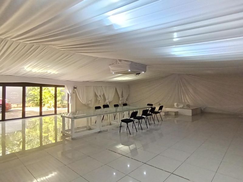 Spacious open-plan area featuring tiled flooring, fabric ceiling draping, and large sliding glass doors providing access to the exterior.