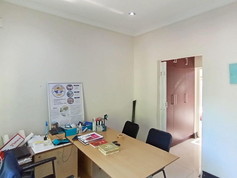 A functional office space featuring tiled flooring, recessed downlighting, and built-in storage cupboards, providing a practical area for work or study.