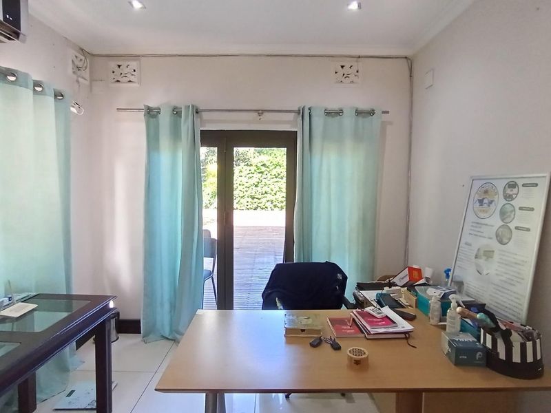 A functional office space featuring tiled flooring, an air conditioning unit, and a sliding glass door providing access to an outdoor area.