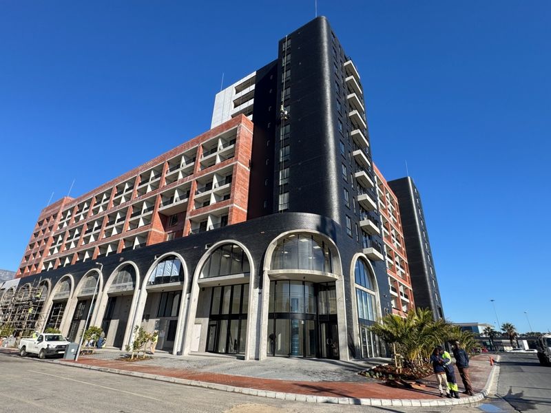 Modern multi-story apartment building featuring a striking black facade with arched ground-level windows and integrated balconies.