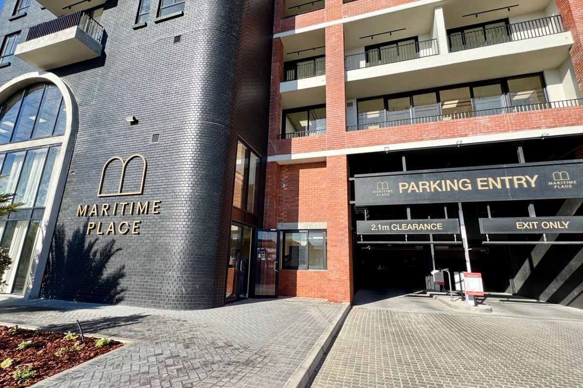 Front exterior view of Maritime Place apartment building, featuring a modern brick facade, secure parking garage entrance, and balconies.
