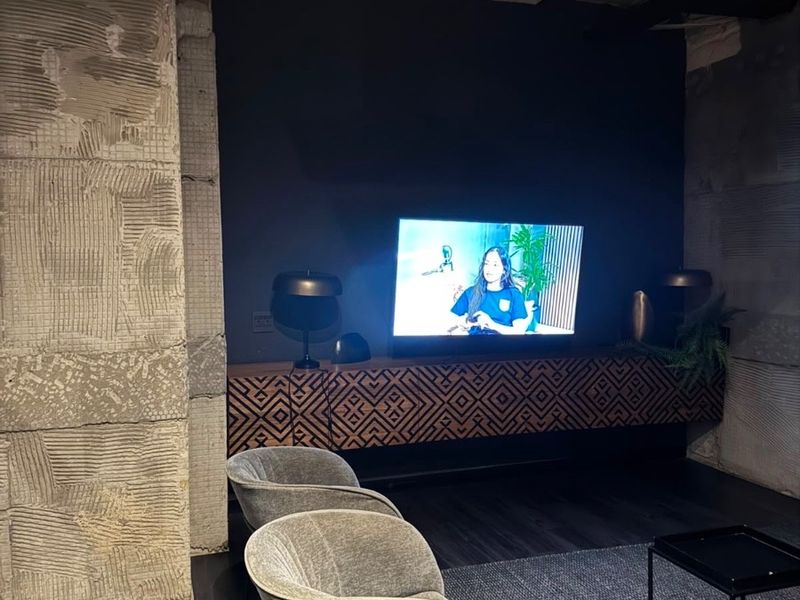 Modern living area featuring industrial-style exposed concrete columns, dark wood flooring, and custom floating cabinetry in a contemporary apartment setting.
