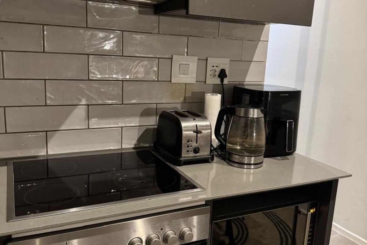 Modern kitchen featuring grey cabinetry, quartz countertops, subway tile backsplash, and integrated stainless steel appliances including an oven, cooktop, and microwave.