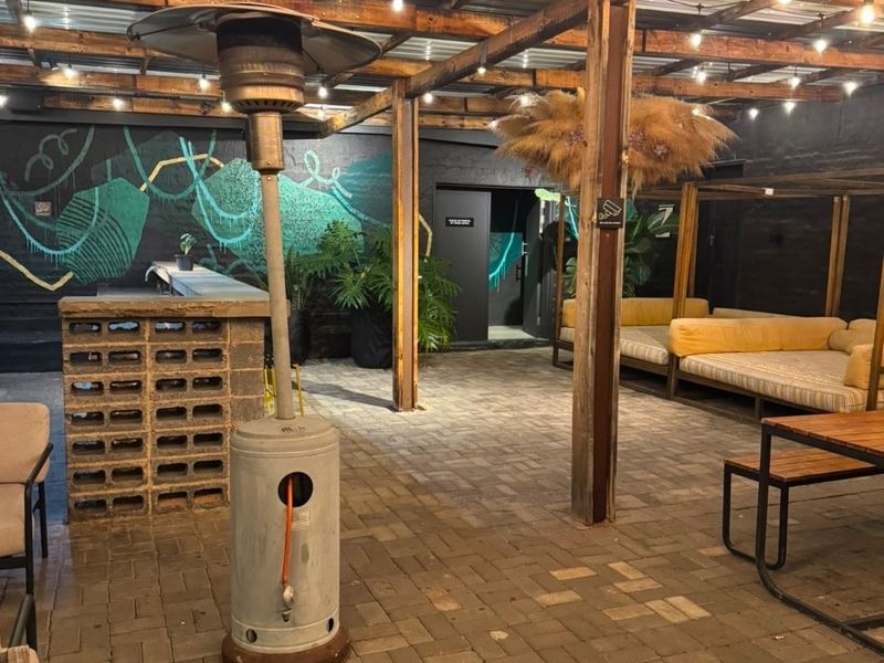 Covered outdoor patio area featuring a timber pergola, paved flooring, and a built-in brick bar, ideal for evening entertainment.