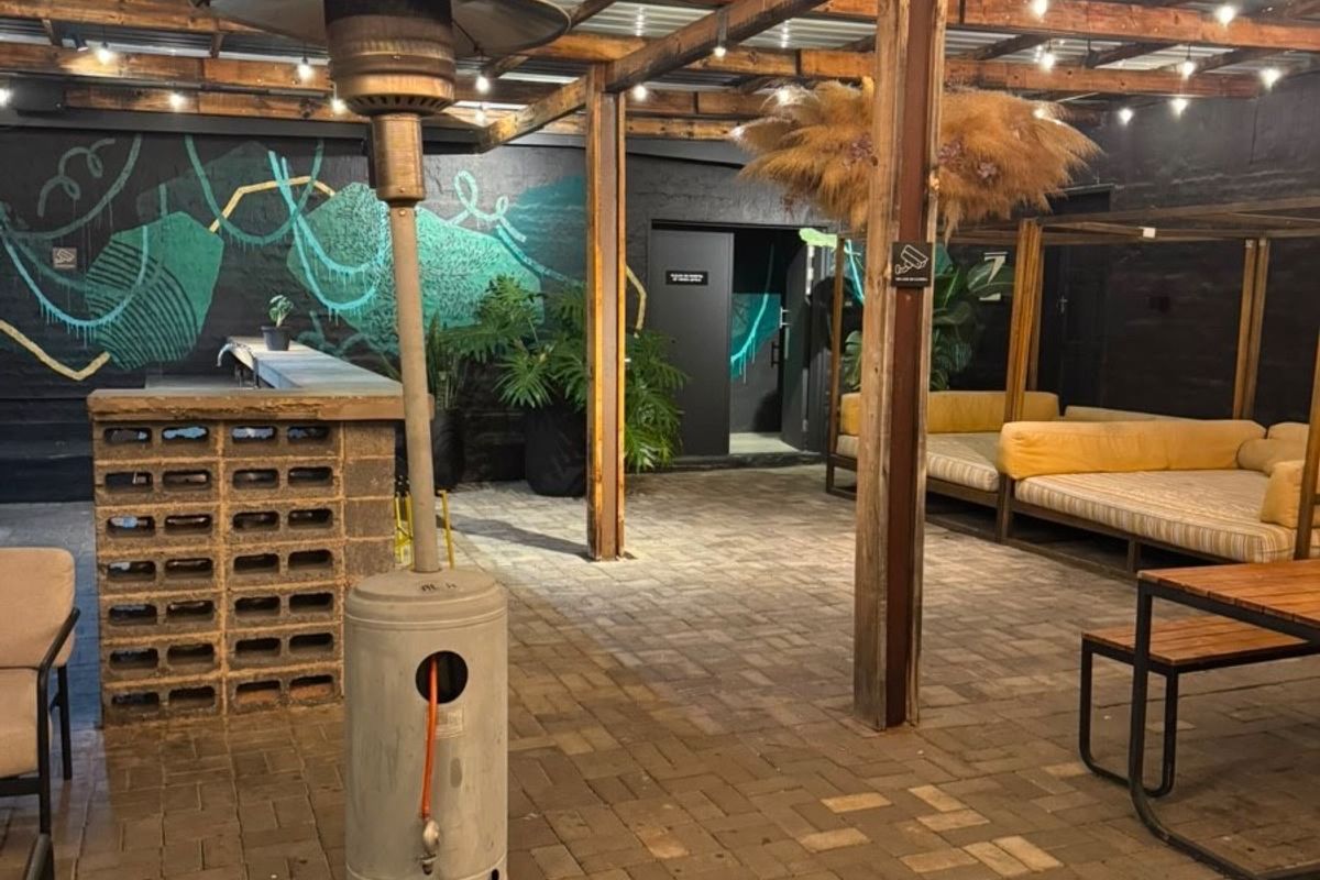 Covered outdoor patio area featuring a timber pergola, paved flooring, and a built-in brick bar, ideal for evening entertainment.