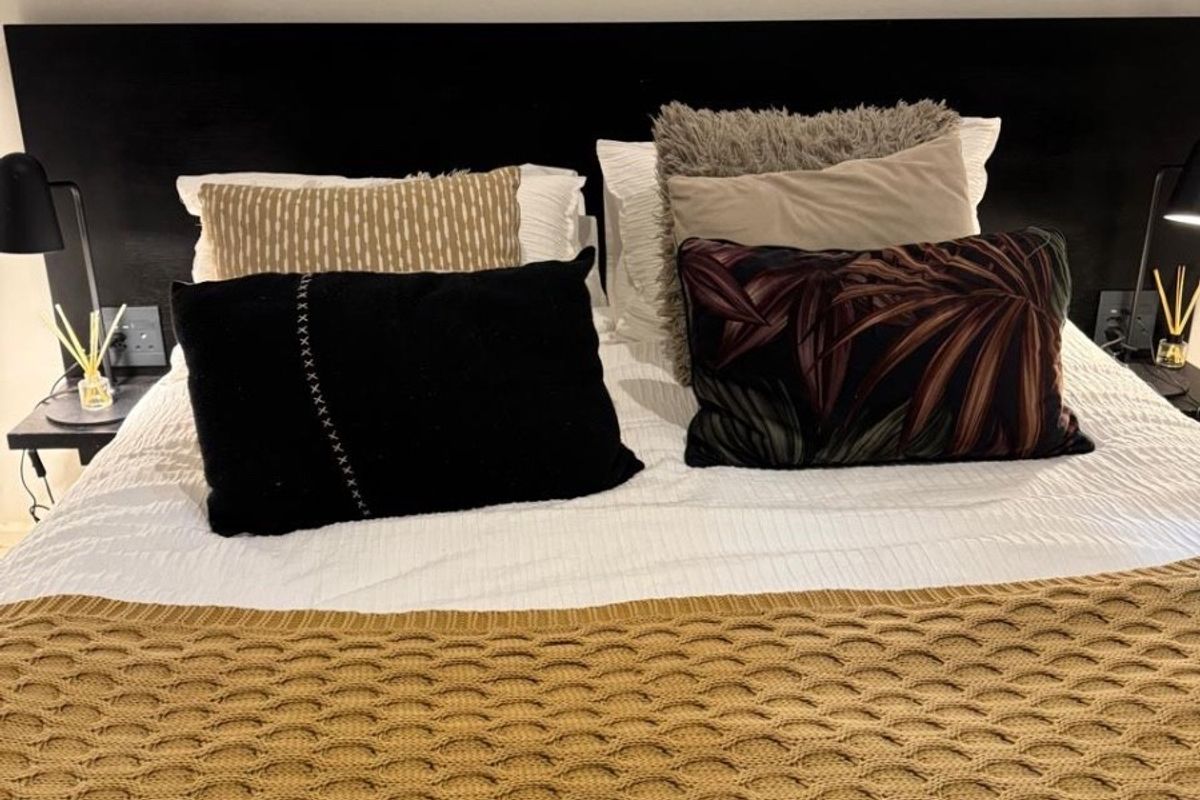 A well-maintained bedroom featuring a modern built-in headboard and integrated electrical outlets.