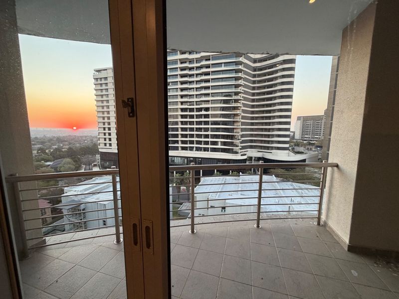 A private balcony featuring tiled flooring and a stainless steel balustrade, offering elevated urban views at sunset.