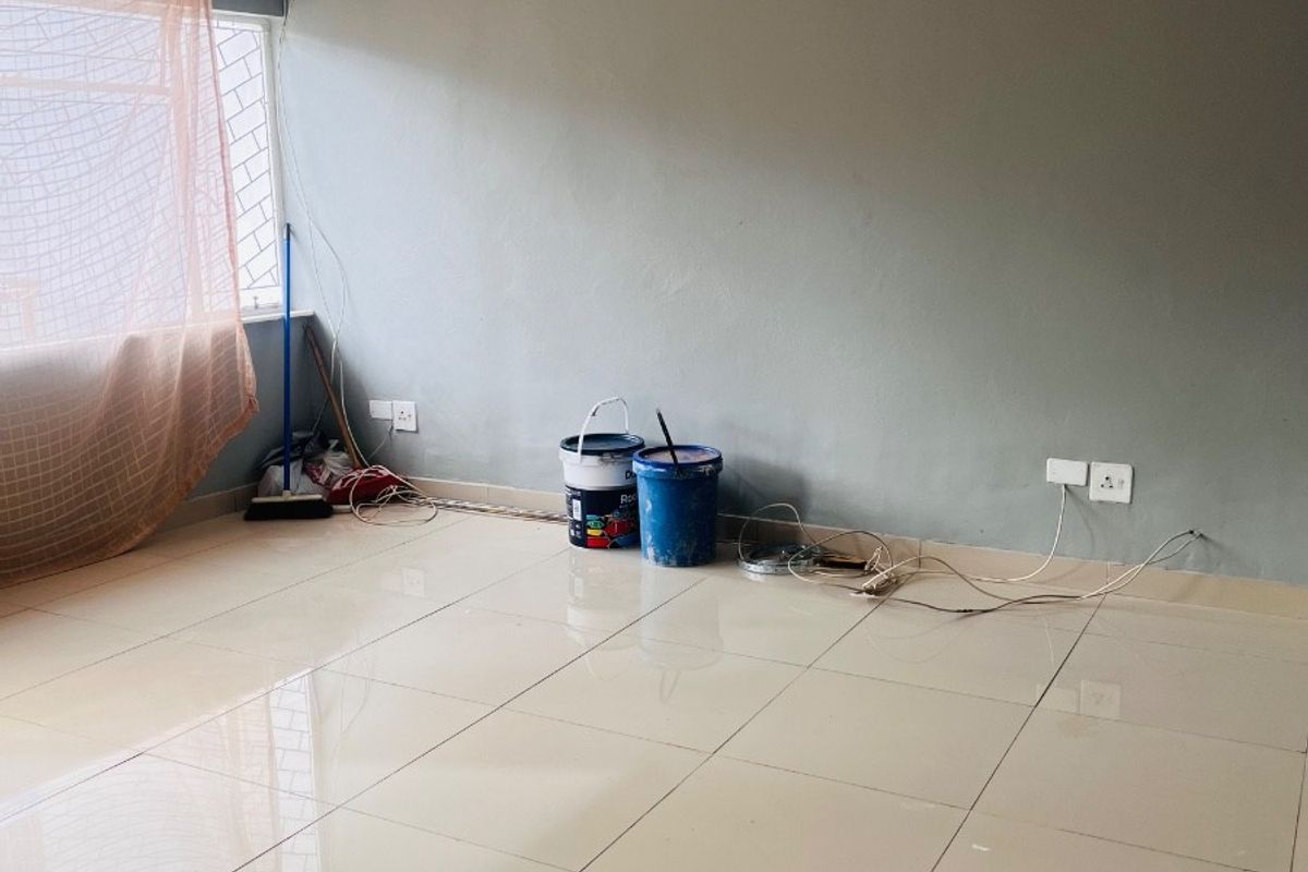 An empty living room featuring neutral tiled flooring, grey painted walls, and security bars on the window.