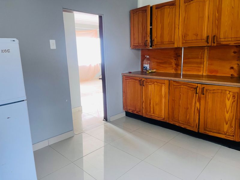A functional kitchen space featuring wooden cabinetry, laminate countertops, and tiled flooring, offering a blank canvas for potential modern updates.