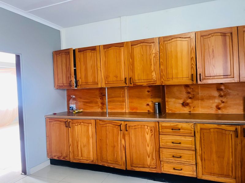 A functional kitchen area featuring extensive wooden cabinetry, a laminate countertop, and tiled flooring, offering a classic aesthetic ready for modern updates.