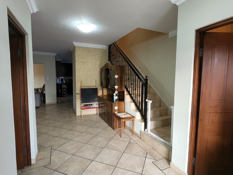 Entrance hall featuring tiled flooring, a staircase with a wrought iron balustrade, and access to adjacent living areas.