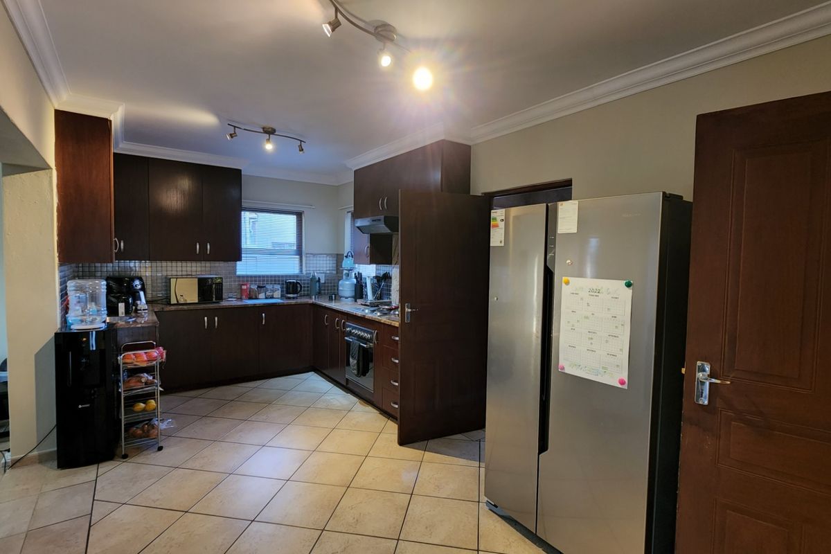 A functional kitchen featuring dark wood cabinetry, tiled flooring, and a tiled backsplash, offering a practical layout for daily meal preparation.