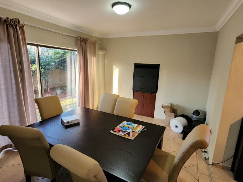 Dining area featuring tiled flooring, built-in storage cabinetry, and a large sliding glass door providing natural light and access to the garden.