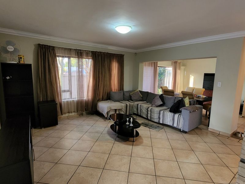 Spacious open-plan living area featuring neutral tiled flooring, a stone-clad feature wall, and direct access to an adjoining dining space.