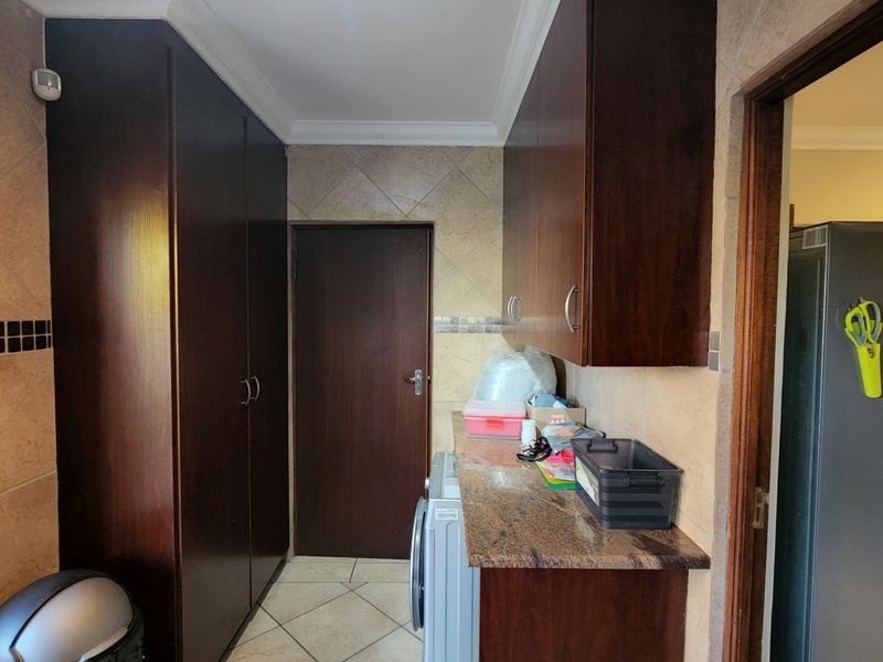 A functional laundry area featuring dark wood built-in cabinetry, granite countertops, and tiled finishes throughout.