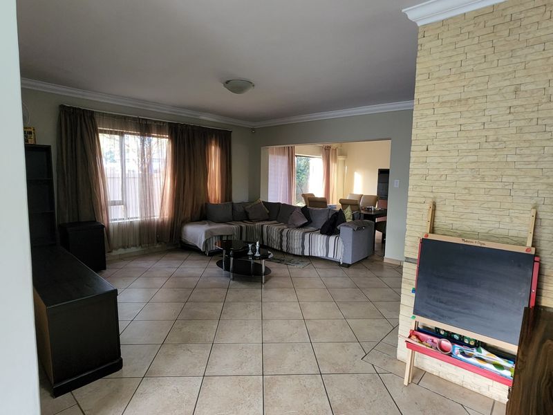 Spacious open-plan living area featuring tiled flooring, a prominent stone-clad feature wall, and large windows allowing for natural light.