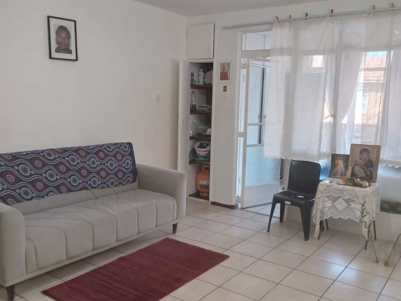 A living room featuring tiled flooring, a built-in storage cupboard, and access to an adjacent outdoor area through a glass panel door.