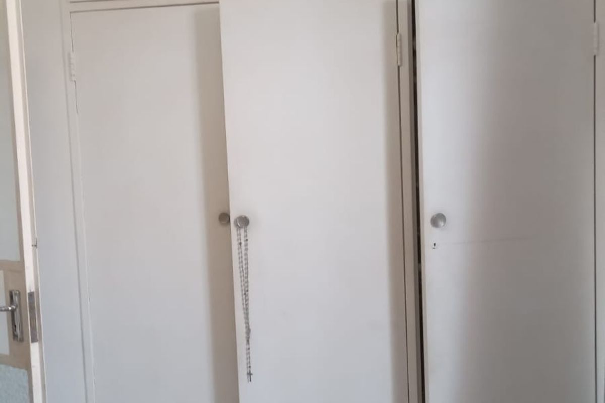 A bedroom featuring white built-in cupboards with overhead storage and tiled flooring throughout.