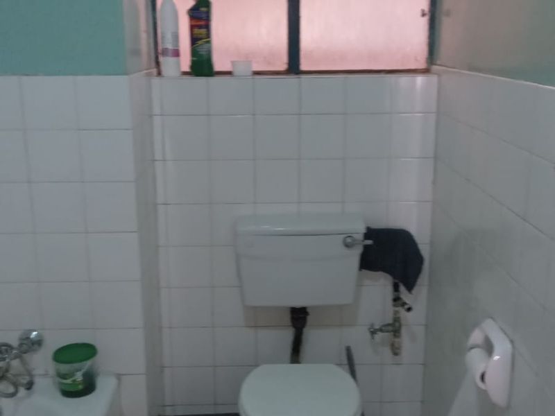 A functional bathroom featuring a standard toilet, bathtub, and tiled surfaces, requiring cosmetic updates to improve its overall aesthetic and condition.