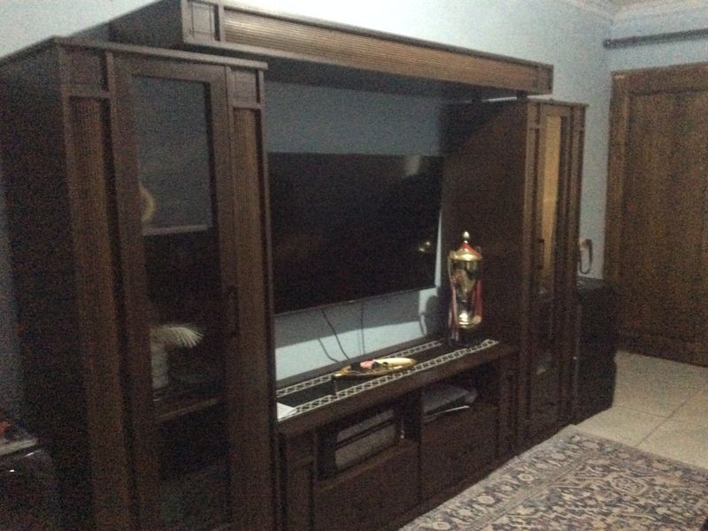 A living room area featuring tiled flooring and a wooden door, captured in a low-light indoor setting.